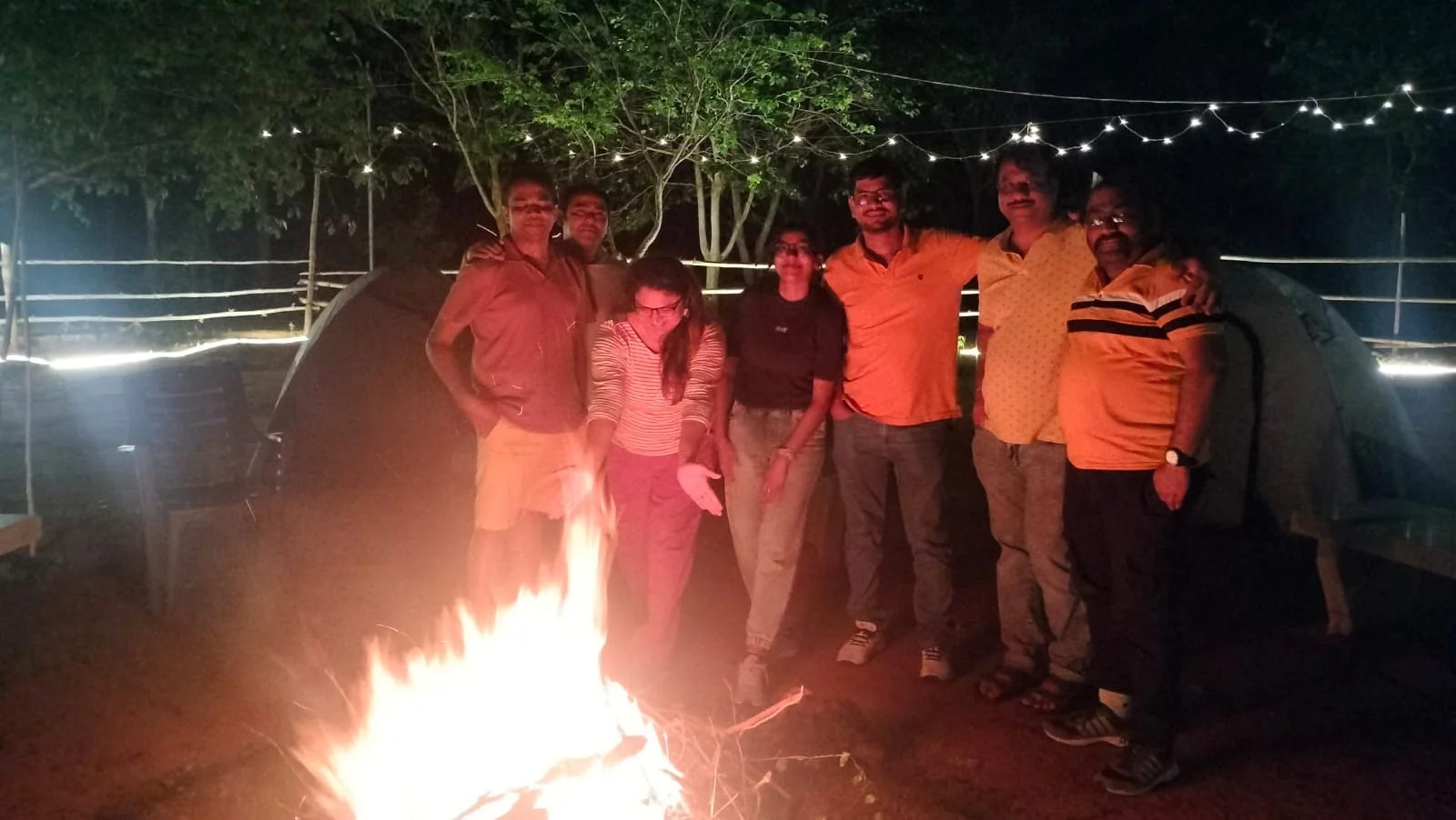 Bonfire with tents and fairy lights at a forest campsite