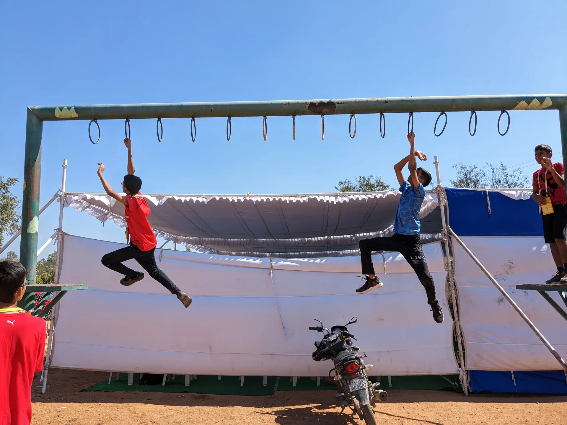Students swinging across monkey bars on an outdoor boot camp obstacle course